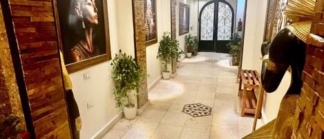 Un couloir agrémenté d’un mur en bois, de plantes en pot et d’œuvres d’art encadrées.