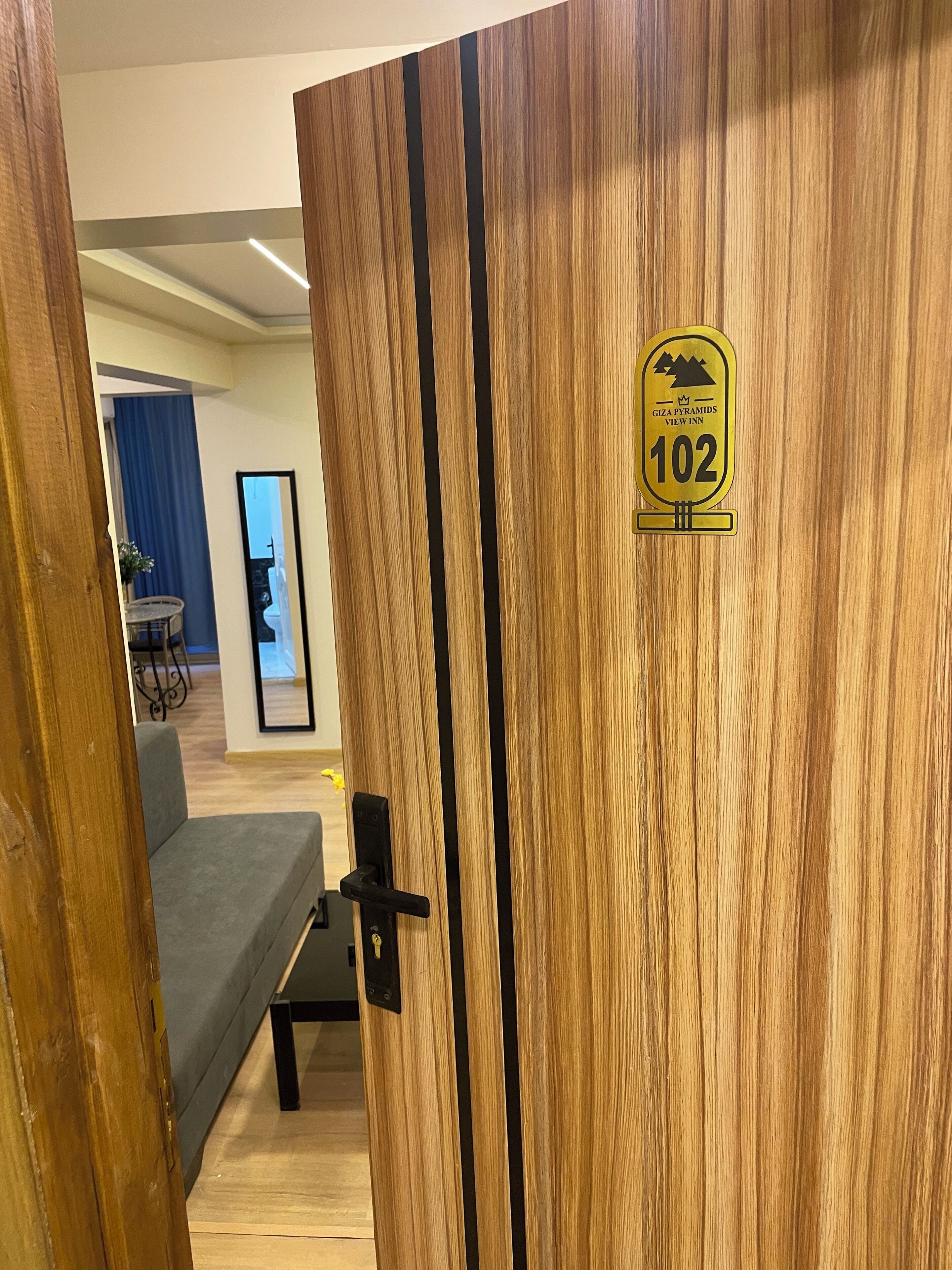 A wooden door with a sign indicating room number 102 at Giza Pyramids View Inn.
