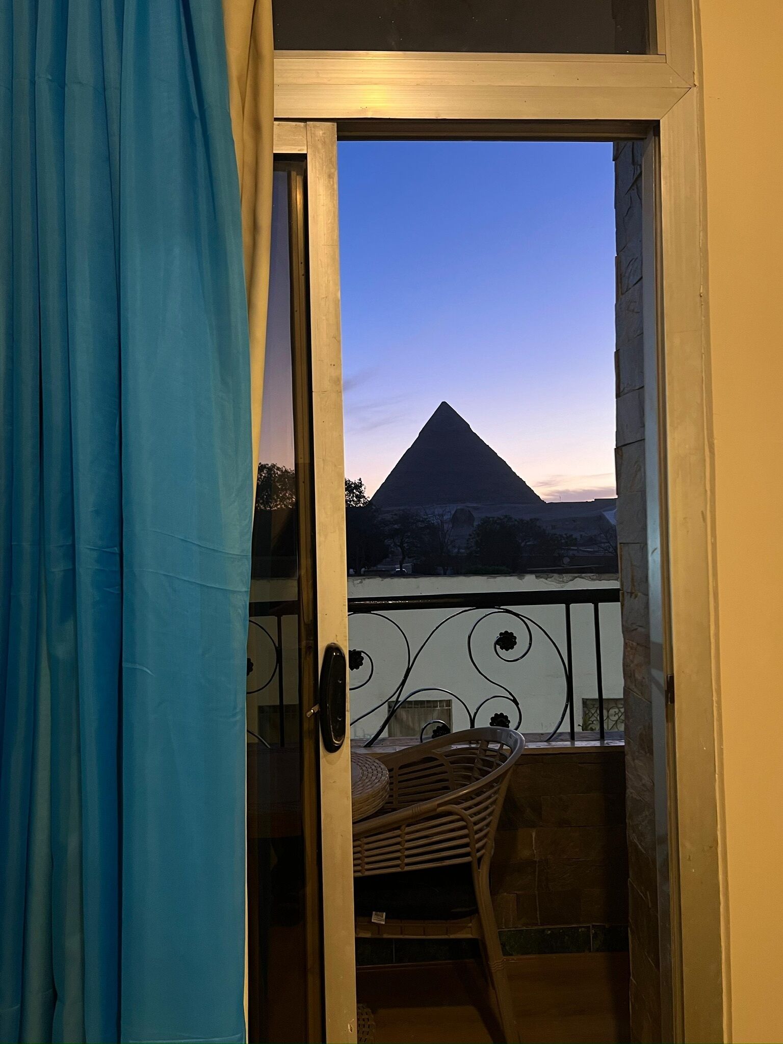 A balcony with a view of a pyramid at sunset.