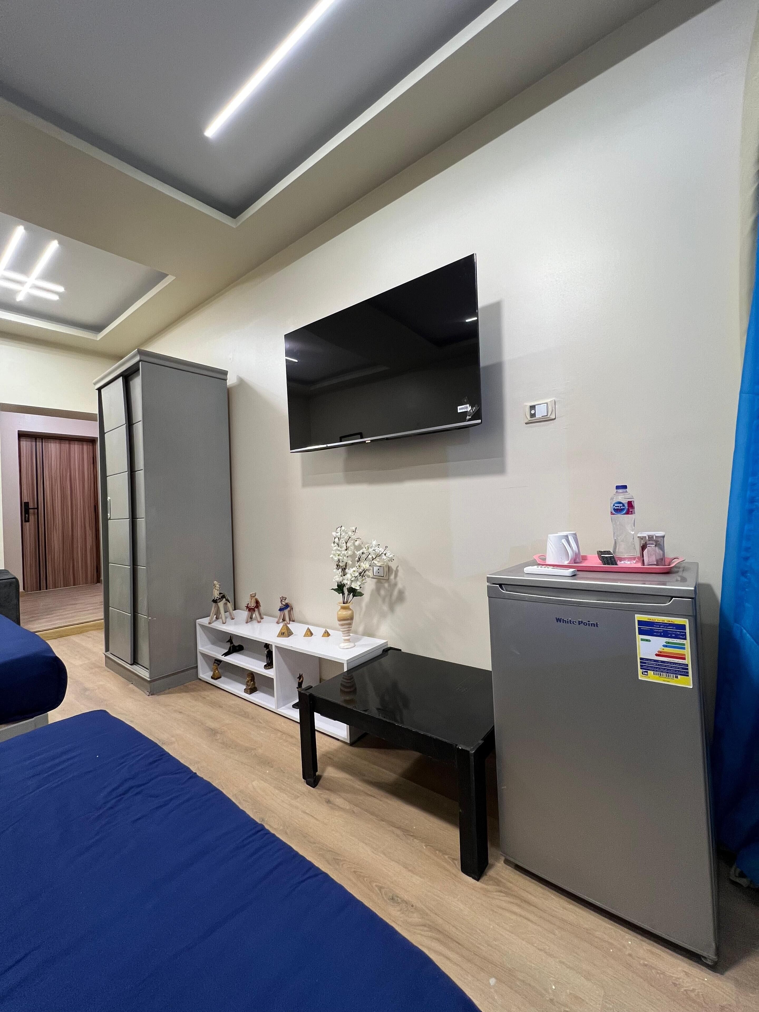 A hotel room with a bed, a desk, a TV, a refrigerator, and a wardrobe.