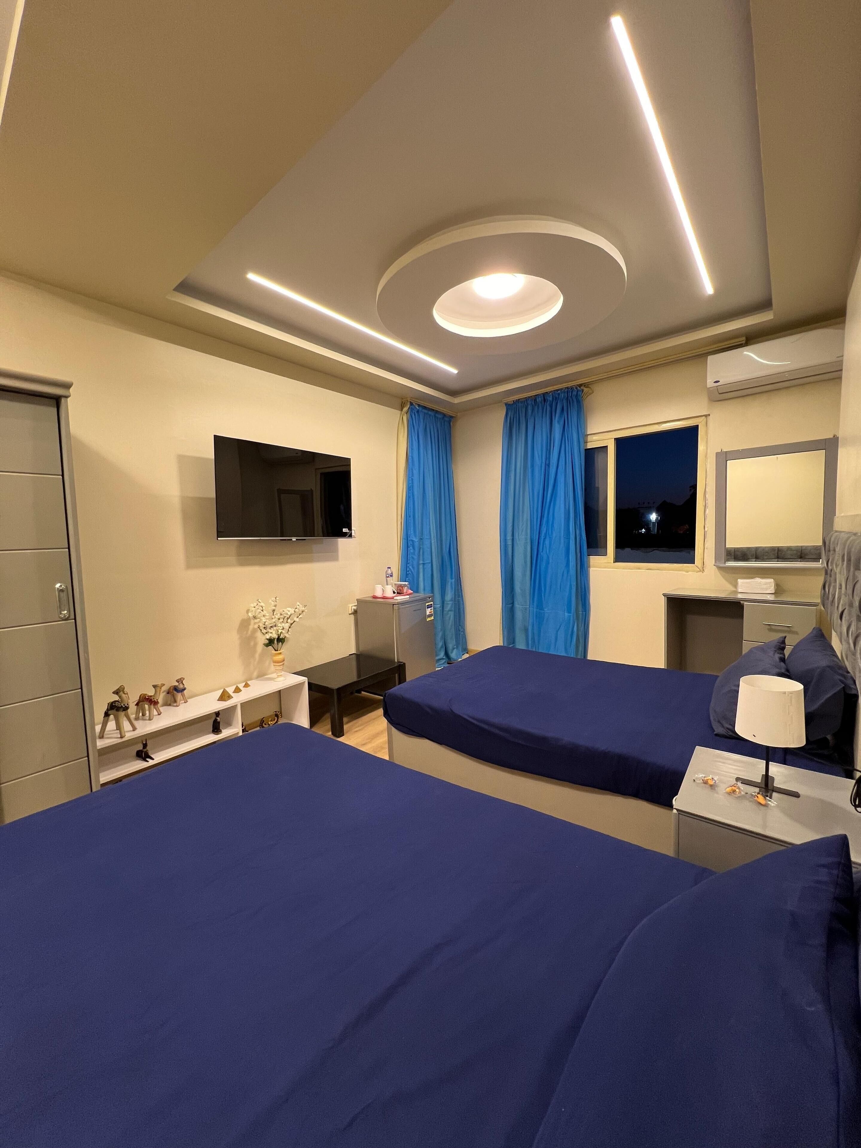 Een hotelkamer met twee bedden, een bureau, een flatscreen televisie en een raam met gordijnen.