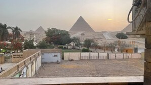 A view of the pyramids at sunset from a rooftop with a stone wall and a sign reading "SOUND & LUXURY HOTEL". - Pyramids View inn Bed & Breakfast (Giza)