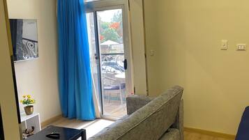 Una sala moderna con un sofá estampado en mármol, una mesita con una planta y un ventanal corredero que da a un área exterior con patio.