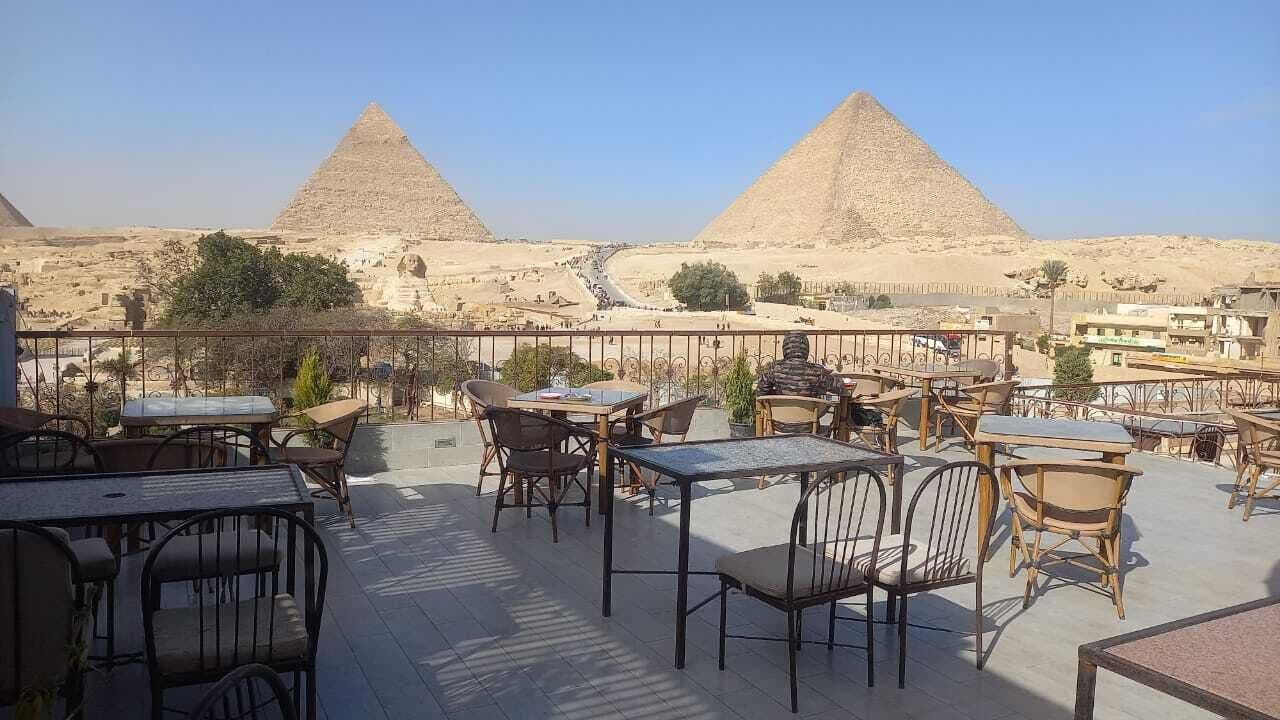 An outdoor seating area with tables and chairs, overlooking the pyramids.