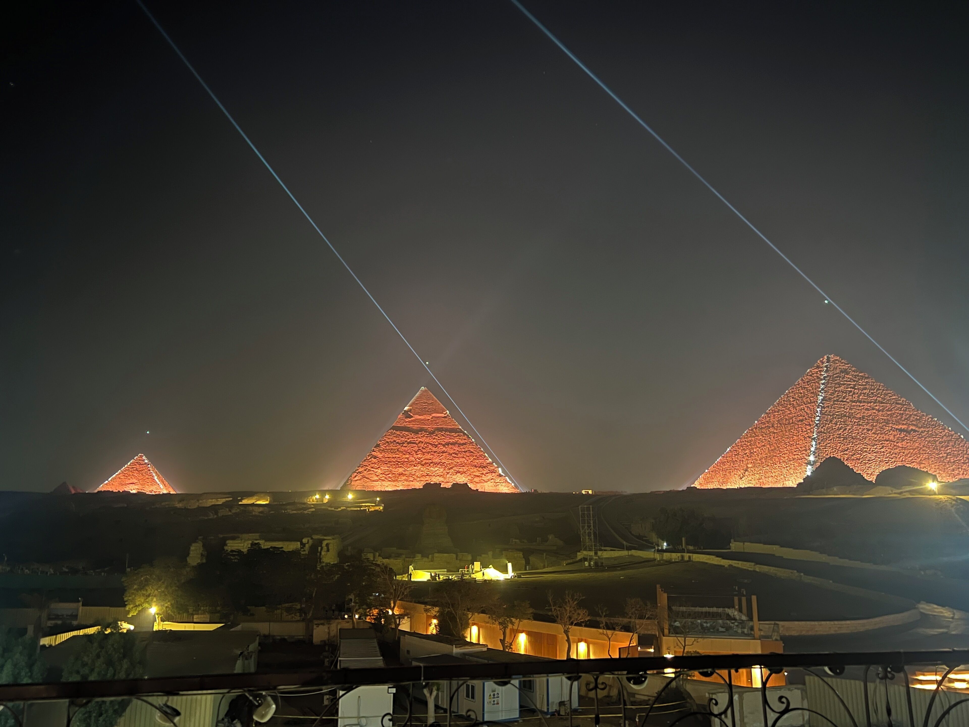 Three illuminated pyramids at night with a clear sky.