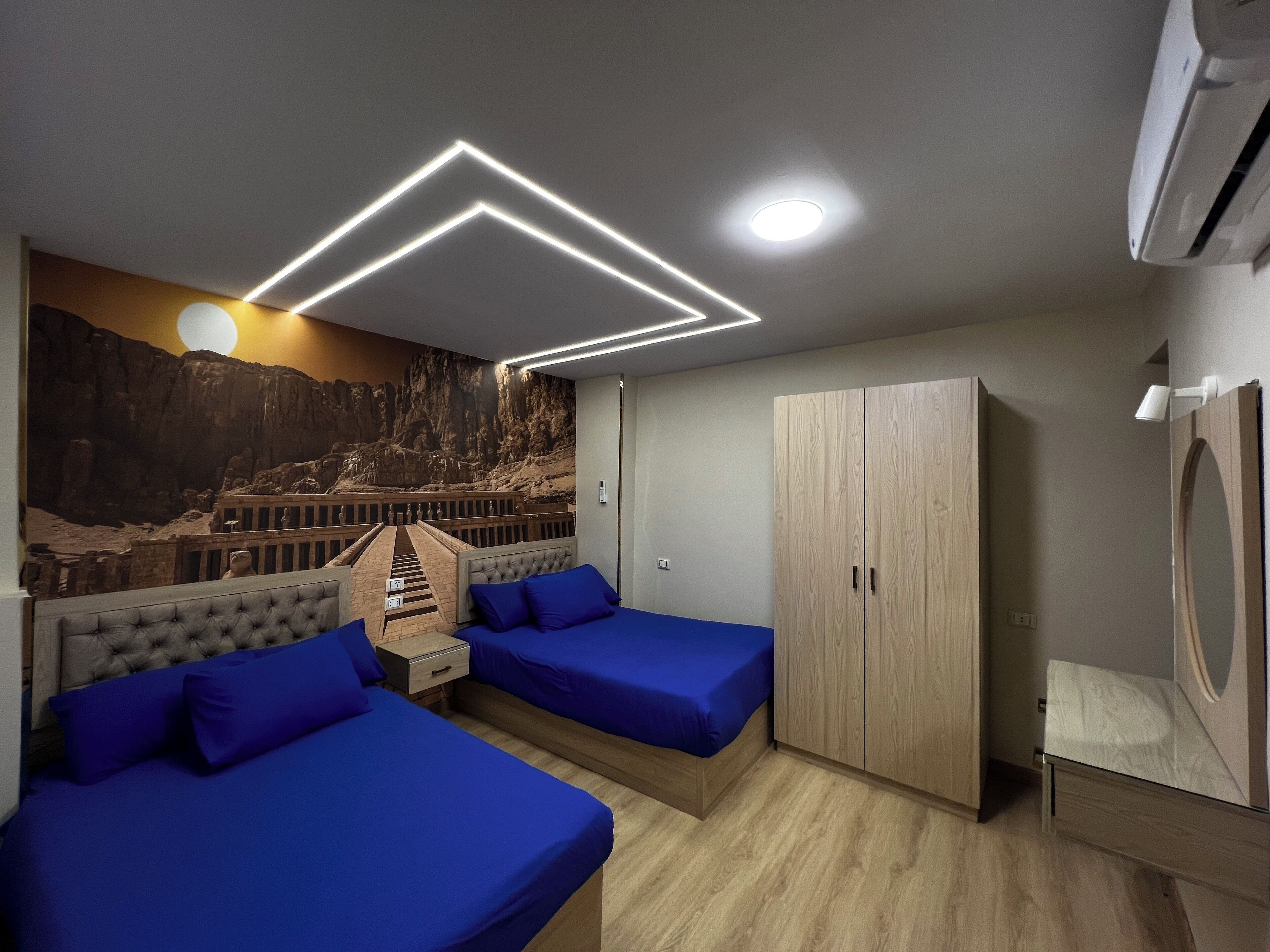 Una camera da letto con due letti, un armadio e un affresco sulla parete.