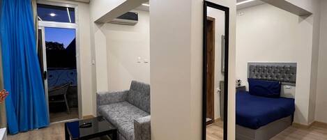 Ein modernes, helles Zimmer mit einer Couch, einem Bett und einem kleinen Tisch.