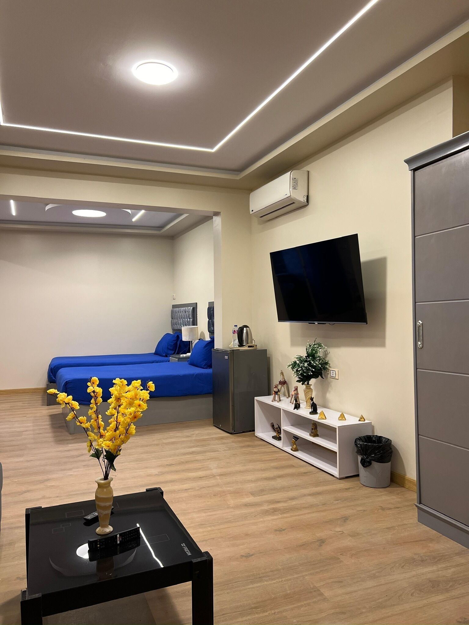 Une chambre d’hôtel moderne avec un lit, une télévision, une petite table avec un vase et un plancher en bois.