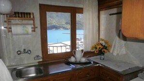Una cocina con armarios de madera, un lavamanos de acero inoxidable y ventana con vistas al agua.