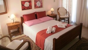 Una habitación de hotel con una cama, dos mesitas de noche, una silla y dos lámparas de pared.