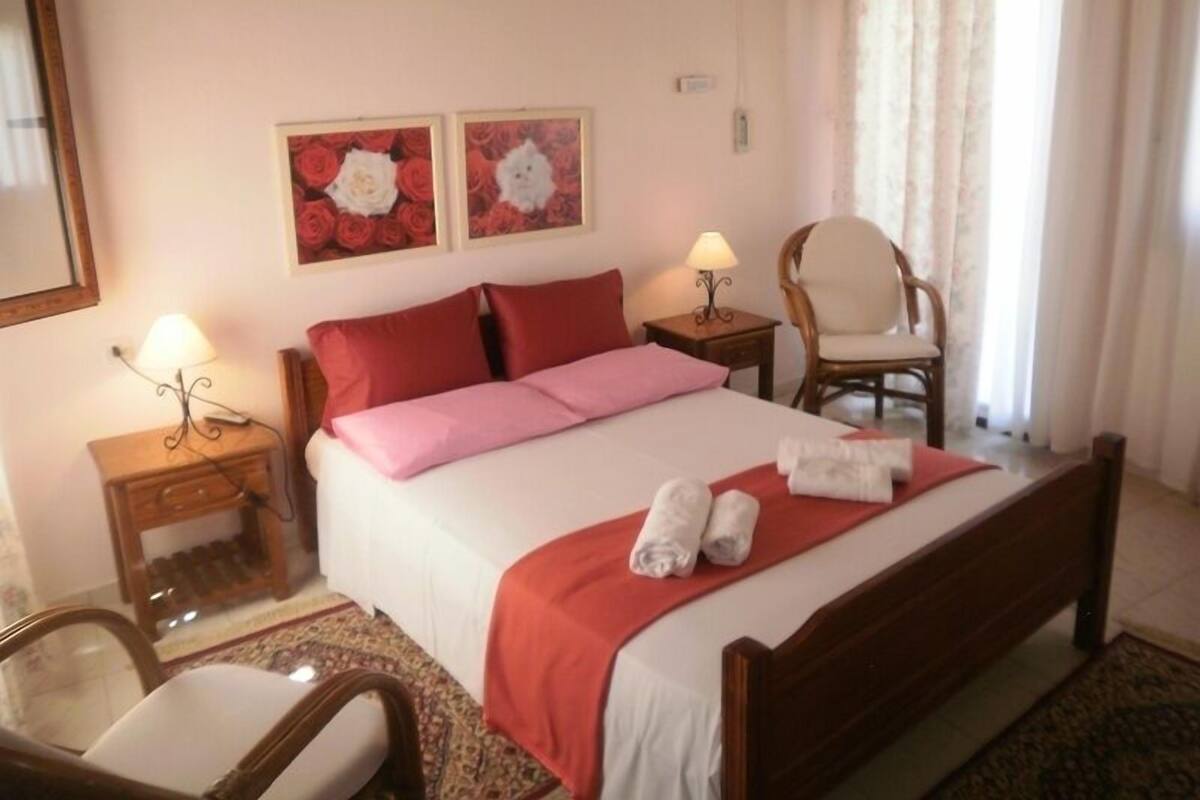 A hotel room with a bed, two bedside tables, a chair, and two wall-mounted lamps.