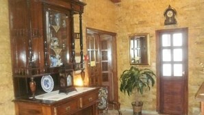 Habitación tradicional con un aparador de madera, un escritorio, dos sillas, una planta en maceta y una alfombra estampada.