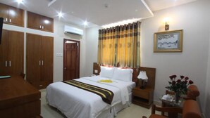A hotel room with a large bed, wooden wardrobe, a small table with a lamp, and a framed picture on the wall. - RedDoorz near Gia Dinh Park (Ho Chi Minh City)
