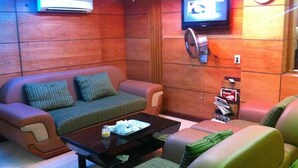 A living room with a sofa, armchairs, a coffee table, a TV, and a magazine rack. - RedDoorz near Gia Dinh Park (Ho Chi Minh City)