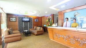 A hotel reception area with a reception desk, two sofas, a TV, and a floral arrangement. - RedDoorz near Gia Dinh Park (Ho Chi Minh City)