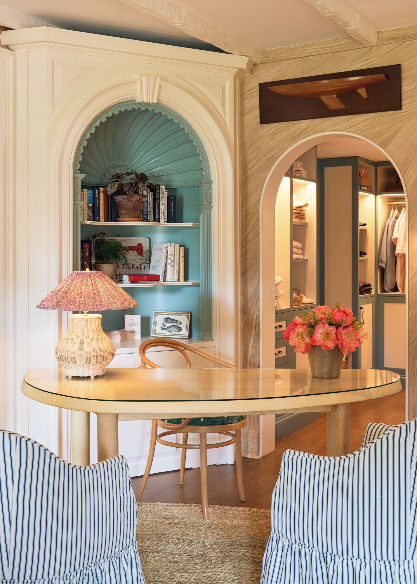 Quarto com mesa de vidro, cadeiras listradas, estante e armário.