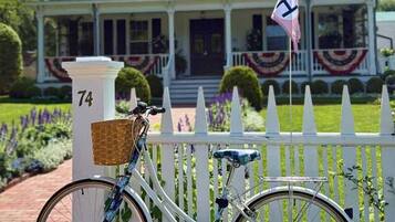 A white house with black shutters, a flag, and a number 74 sign.
