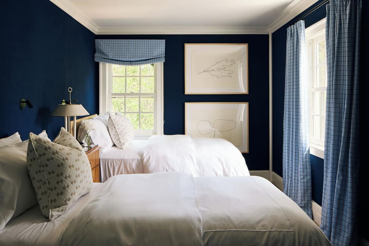 A bedroom with two beds, a window with a view, and framed artwork on the wall.