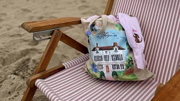 Une chaise de plage avec un coussin à rayures et un sac orné de motifs floraux.