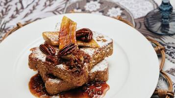 A dessert on a white plate with pecans and a fruit slice, placed on a patterned tablecloth.