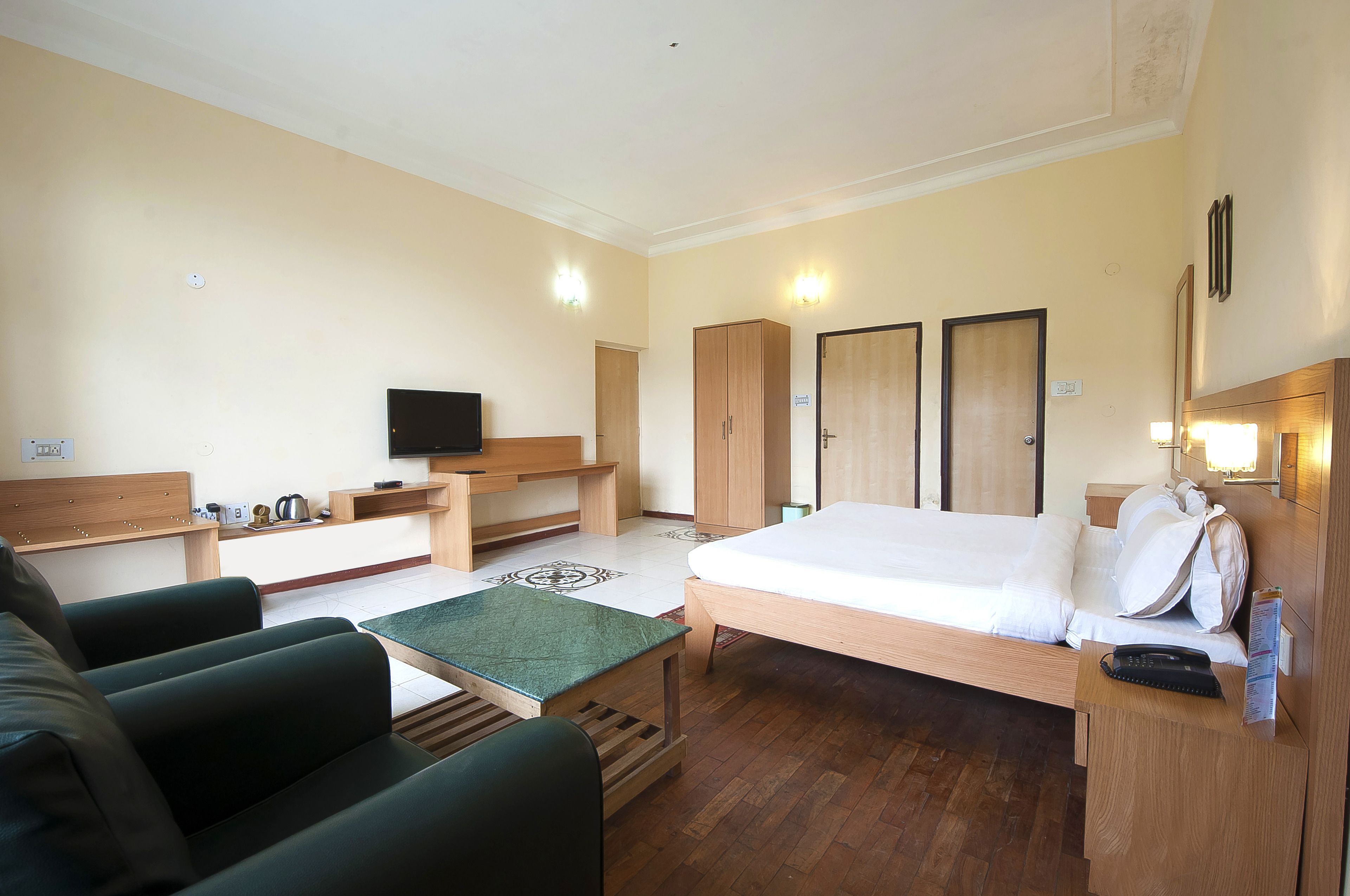 A hotel room with a bed, a sofa, a desk, a television, and a wardrobe.