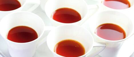 A tray with multiple white cups filled with a dark liquid, likely tea or coffee.