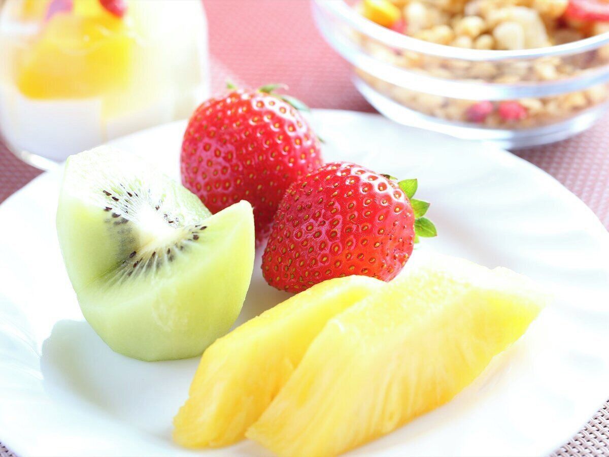 A plate with sliced kiwi, strawberries, and pineapple.
