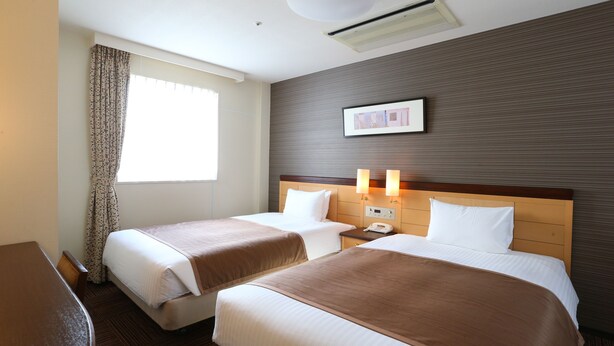 A hotel room with two beds, a wooden headboard, a bedside table with a lamp, a window with curtains, and a wall-mounted picture. - Hotel Hokke Club Sapporo (Sapporo)