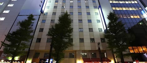 Ein mehrstöckiges Hotel mit moderner Fassade, großen Fenstern und einem Eingangsbereich mit roter Markise.
