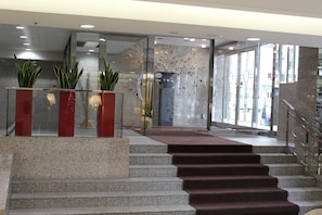 A modern hotel lobby with granite steps, glass doors, and potted plants. - Hotel Hokke Club Sapporo (Sapporo)