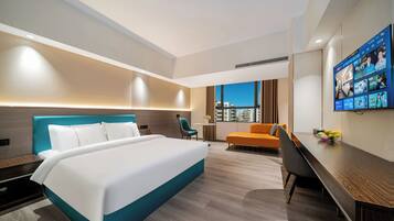 Relax in a stylish room with a large bed, desk, and seating area, offering a city view.