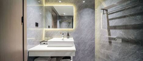 A modern bathroom with a large mirror, a white sink, and a towel rack.