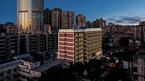 A high-rise building with a modern glass facade and a traditional brick building with illuminated signage in the foreground. - Guangzhou Meigang Hotel (Guangzhou)