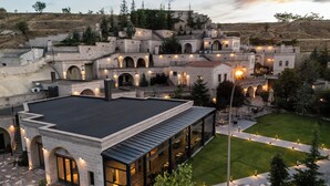 Hotel moderno com terraço no telhado, arquitetura em pedra e iluminação externa.