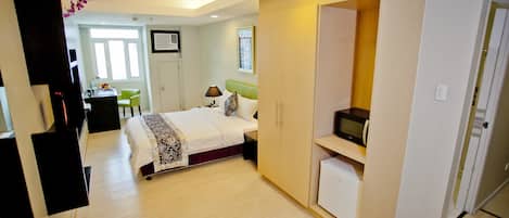 Una habitación de hotel moderna con cama, escritorio, silla y armario.
