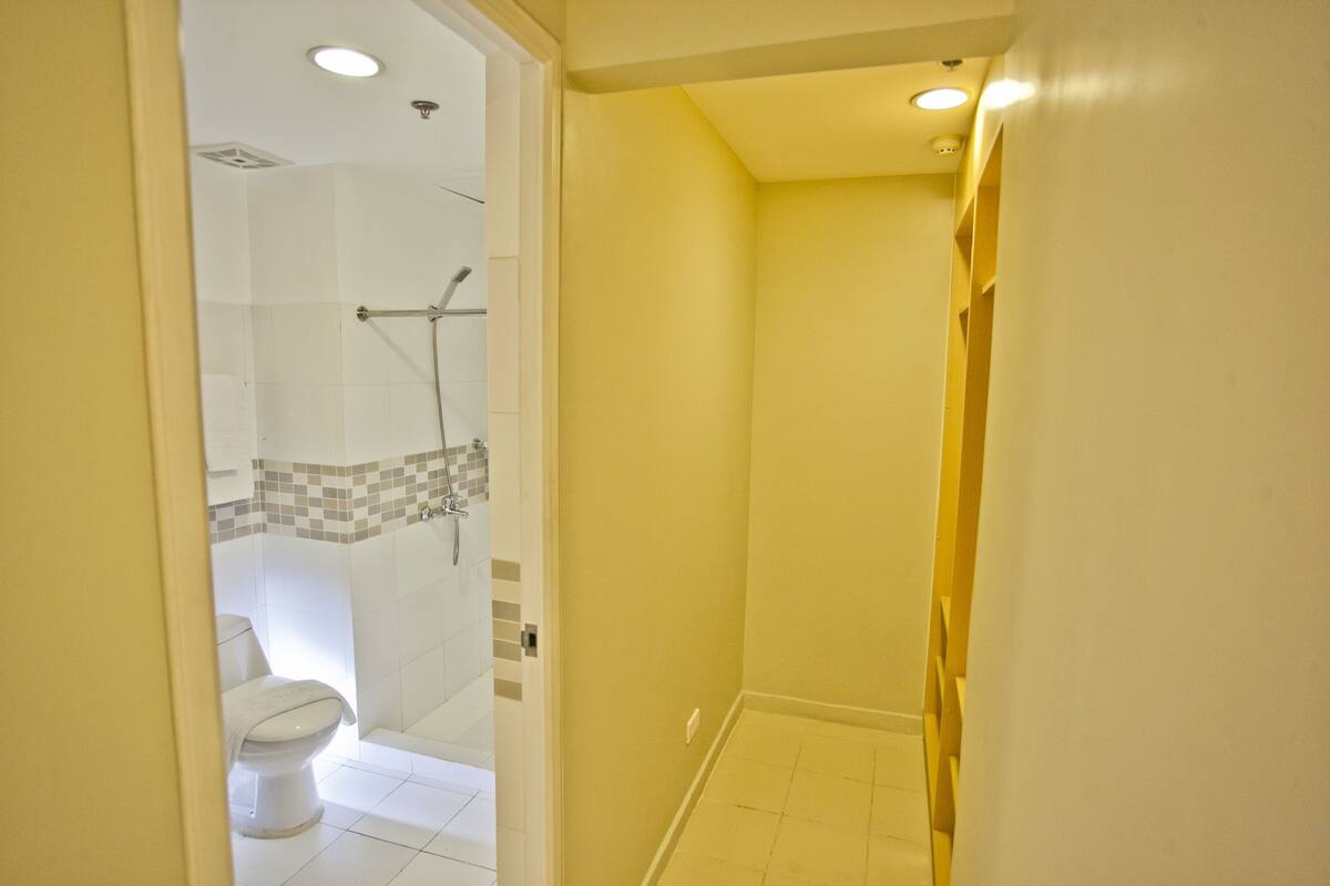 A bathroom with a shower, toilet, and a tiled floor.