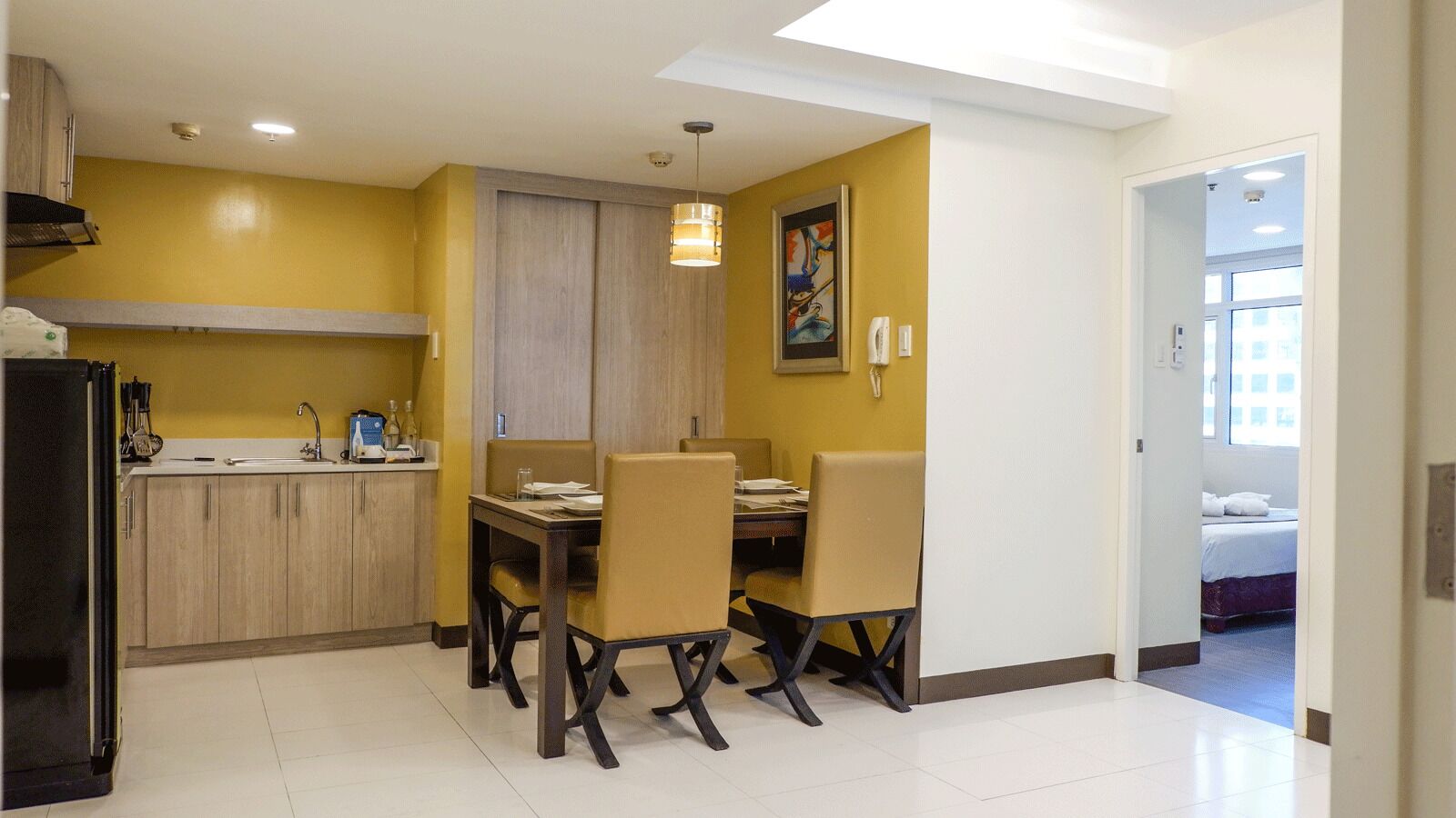 Una cocina compacta con comedor, un refrigerador y un cuadro en la pared.