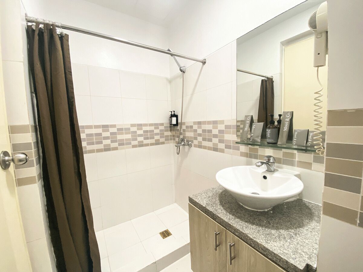 A bathroom with a shower, a sink, and a mirror.