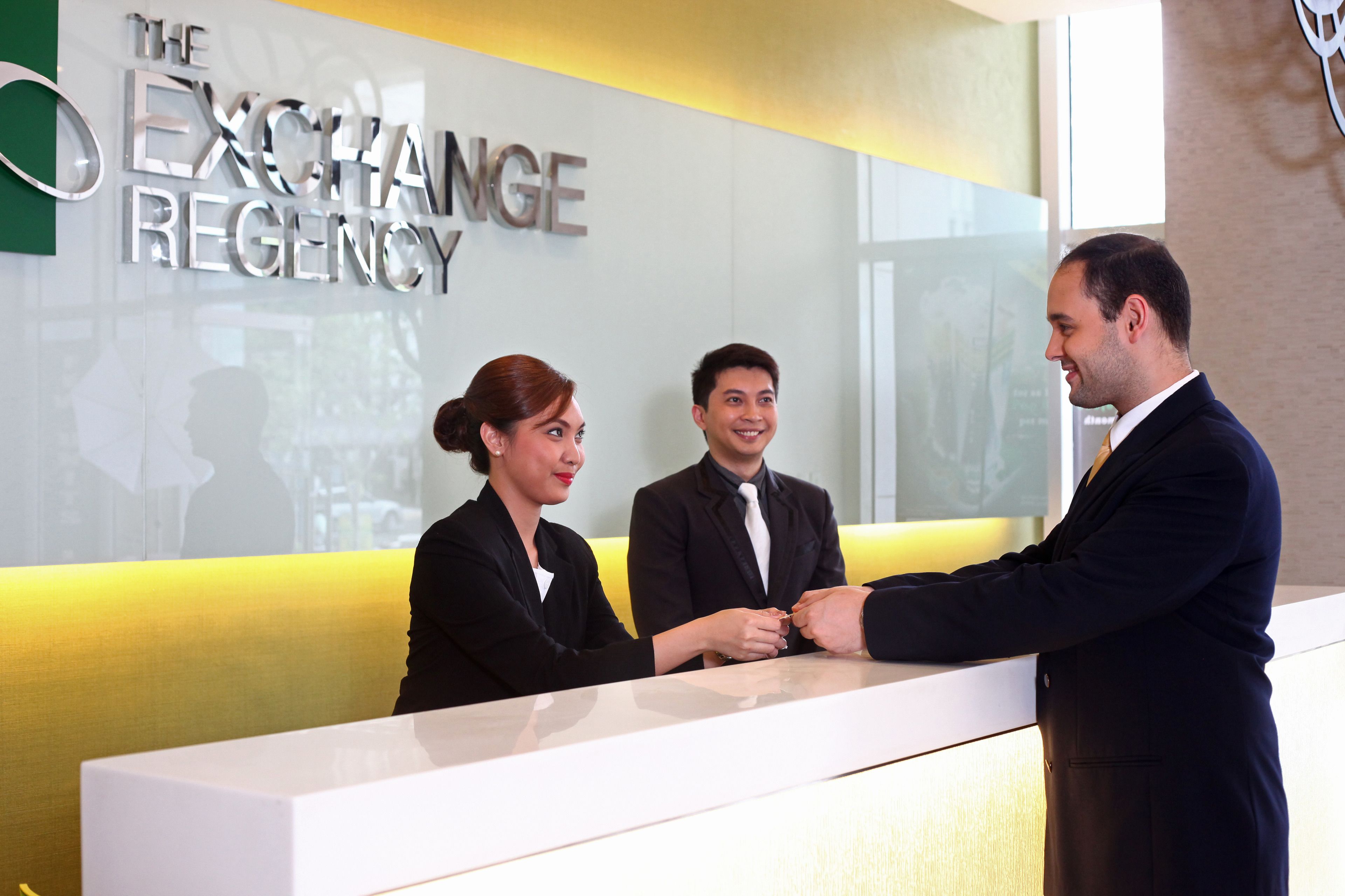 A reception desk at The Exchange Regency with a modern design and a glass partition.