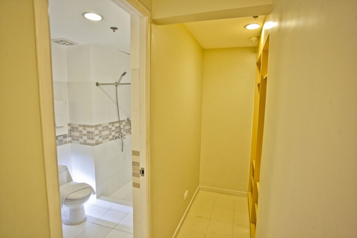 A narrow hallway with a shower area and a toilet.