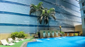A swimming pool with lounge chairs and palm trees. - The Exchange Regency Residence Hotel (Pasig)