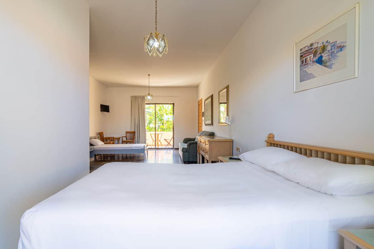 A hotel room with a large bed, a desk, a chair, and a view of the outdoors.