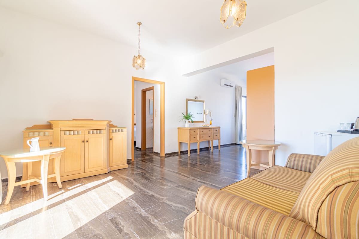 A spacious living room with a sofa, a wooden cabinet, a small table, and a hanging light fixture.