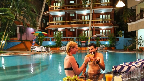 Un bar a la piscina amb una barra, una piscina i un edifici de diversos pisos al fons.