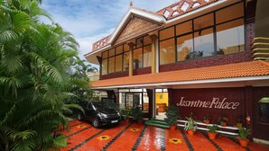 Un edifici amb un cartell que diu "Jasmine Palace" i una zona de pàrquing amb un SUV negre.