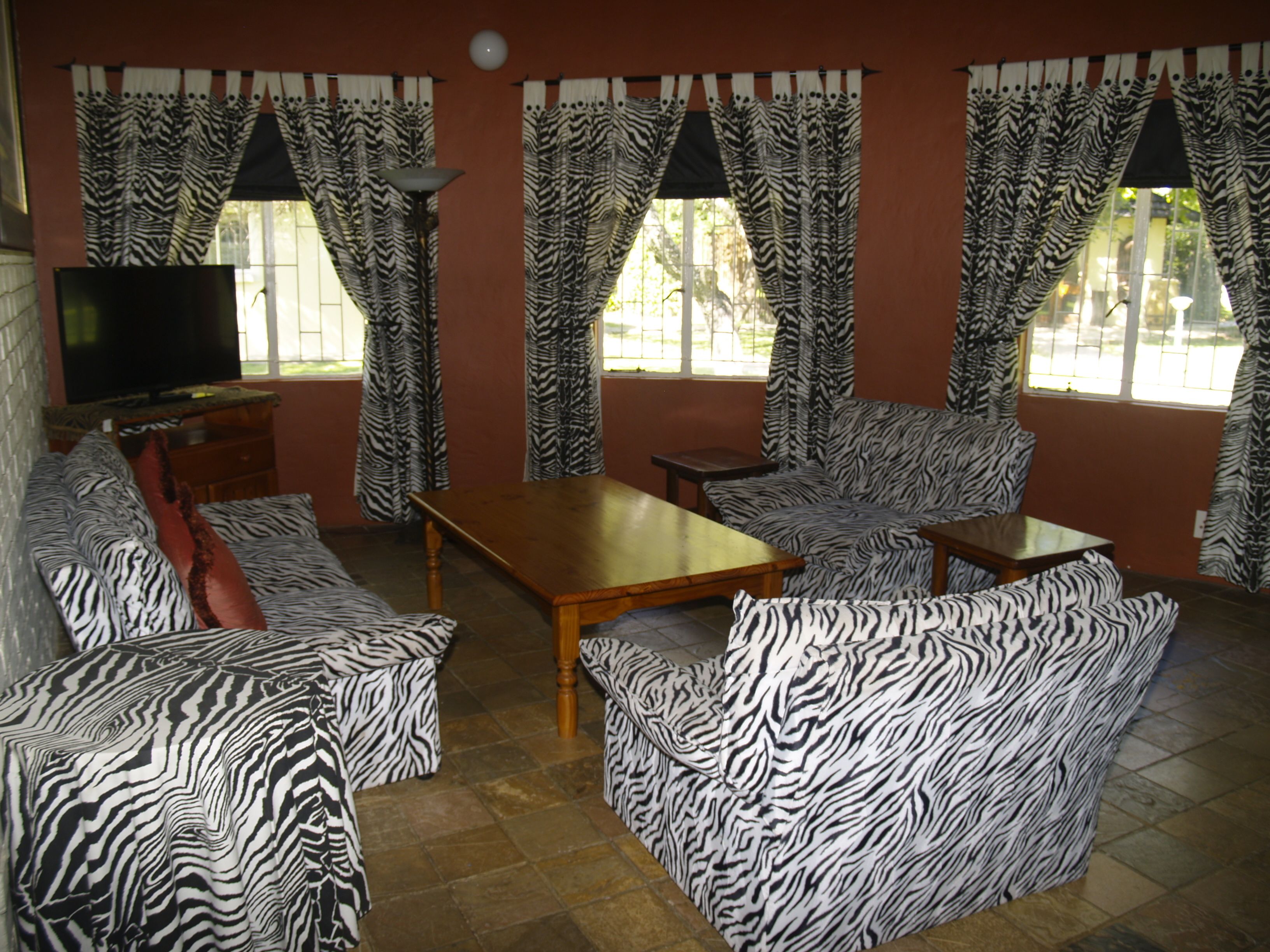 A living room with zebra-patterned sofas, a wooden coffee table, and curtains with a zebra print.