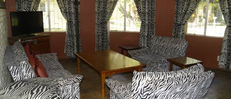 A living room with zebra-patterned sofas, a wooden coffee table, and curtains with a zebra print.