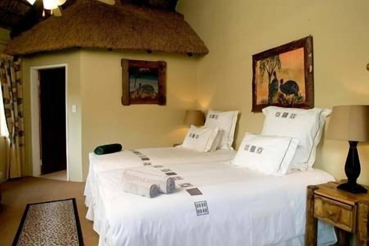 Ein Hotelzimmer mit einem Bett, einem Nachttisch, einer Lampe, einer Tür und einem Bild an der Wand.