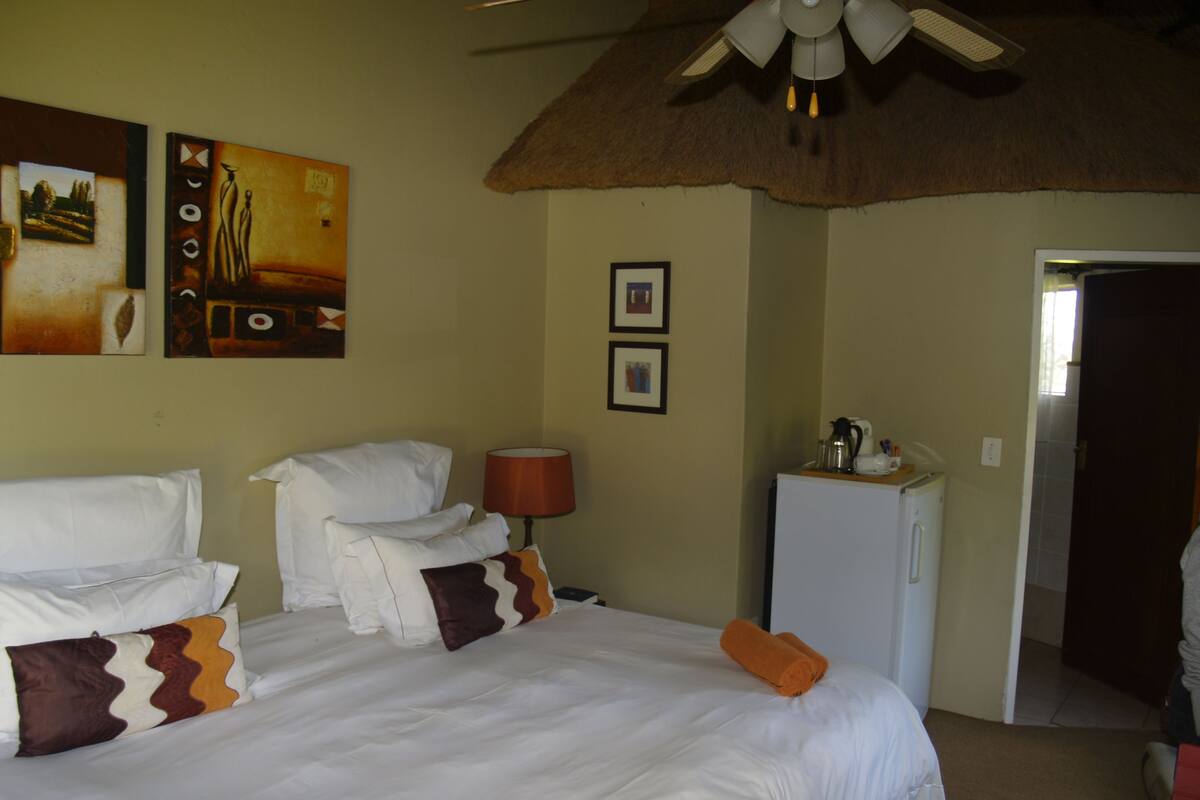Ein Hotelzimmer mit Bett, Schreibtisch, Lampe und Kühlschrank.