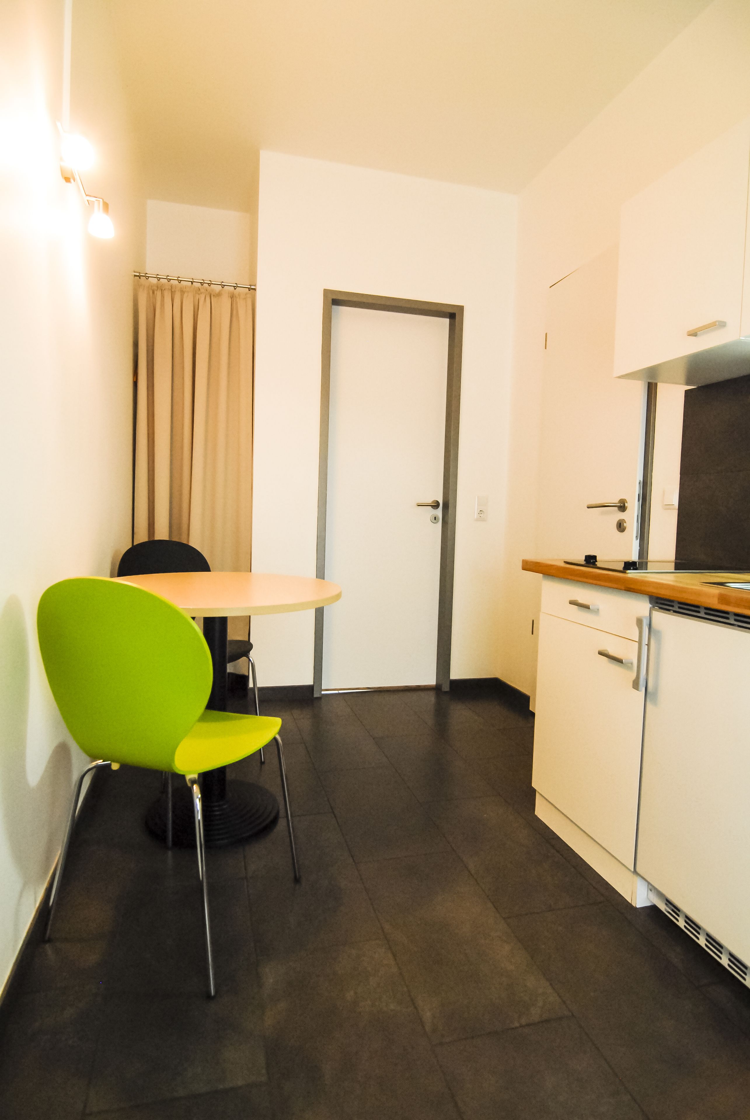 A small, clean kitchen with a single table and a bright green chair.